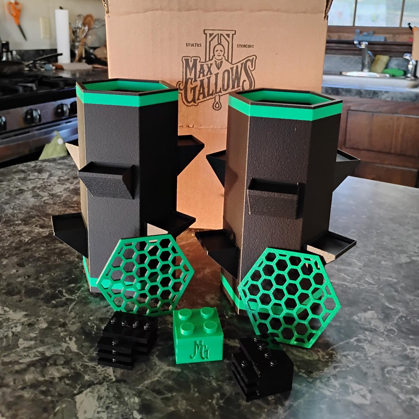 Black and green geometric vases on a kitchen counter with a cardboard box labeled 'Max Gallows' in the background.