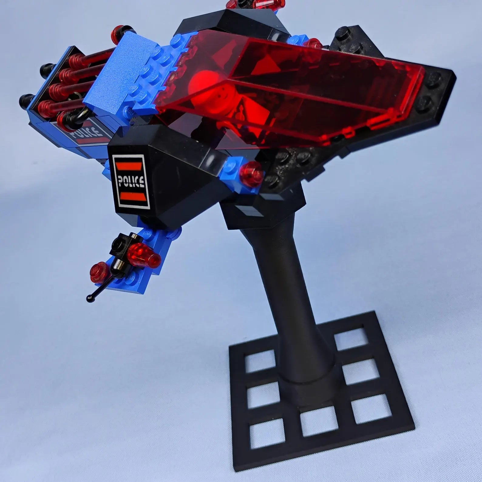 Black adjustable display stand holding a LEGO® spaceship at an angled pose, designed for dramatic shelf or desk display.