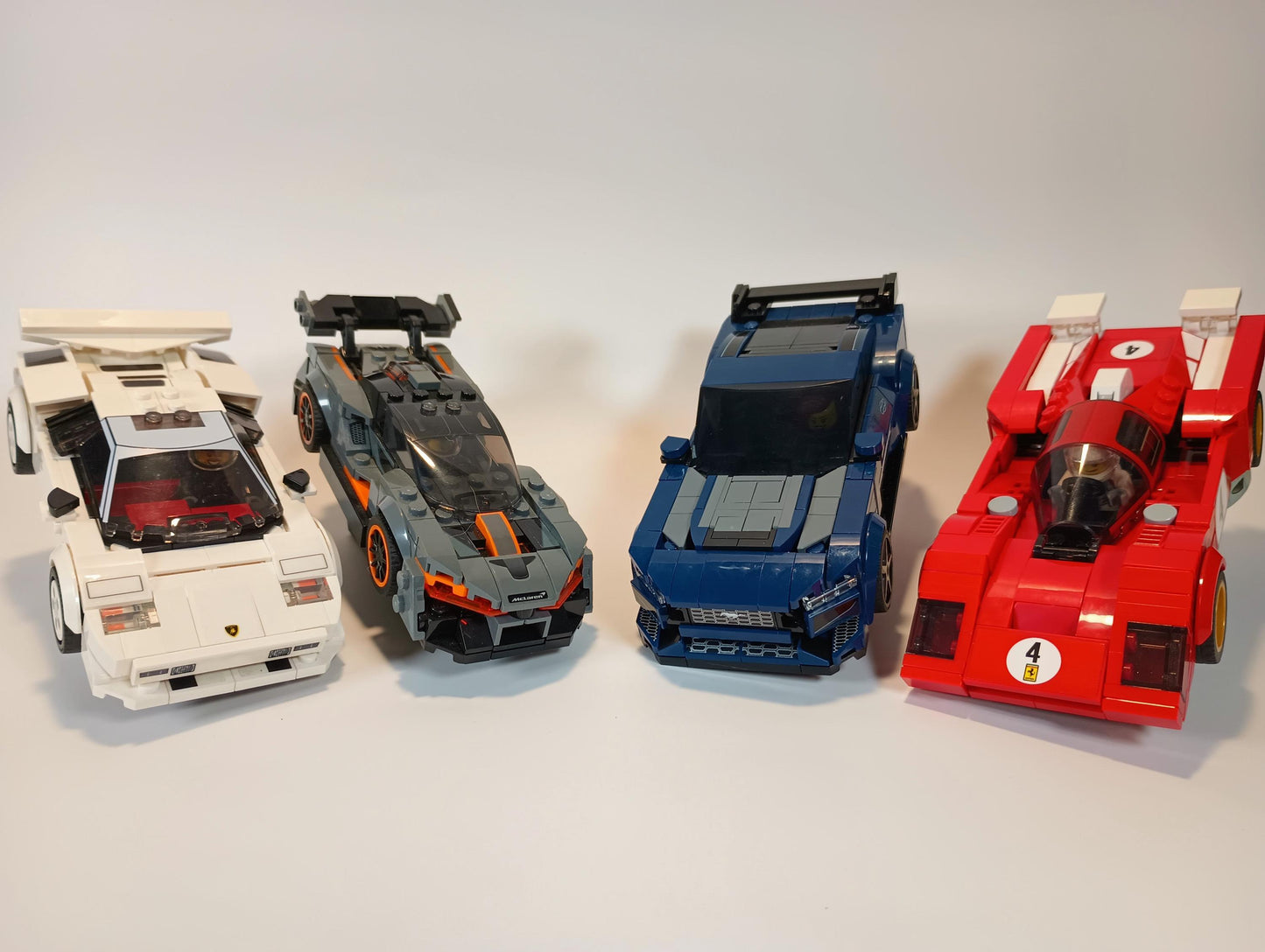 Four LEGO® Speed Champions style cars displayed on angled stands