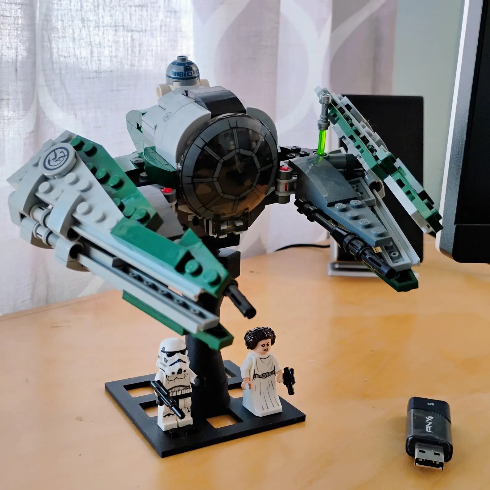 LEGO® Star Wars style TIE Fighter displayed on a black adjustable stand with minifigure base area and desk display setup.