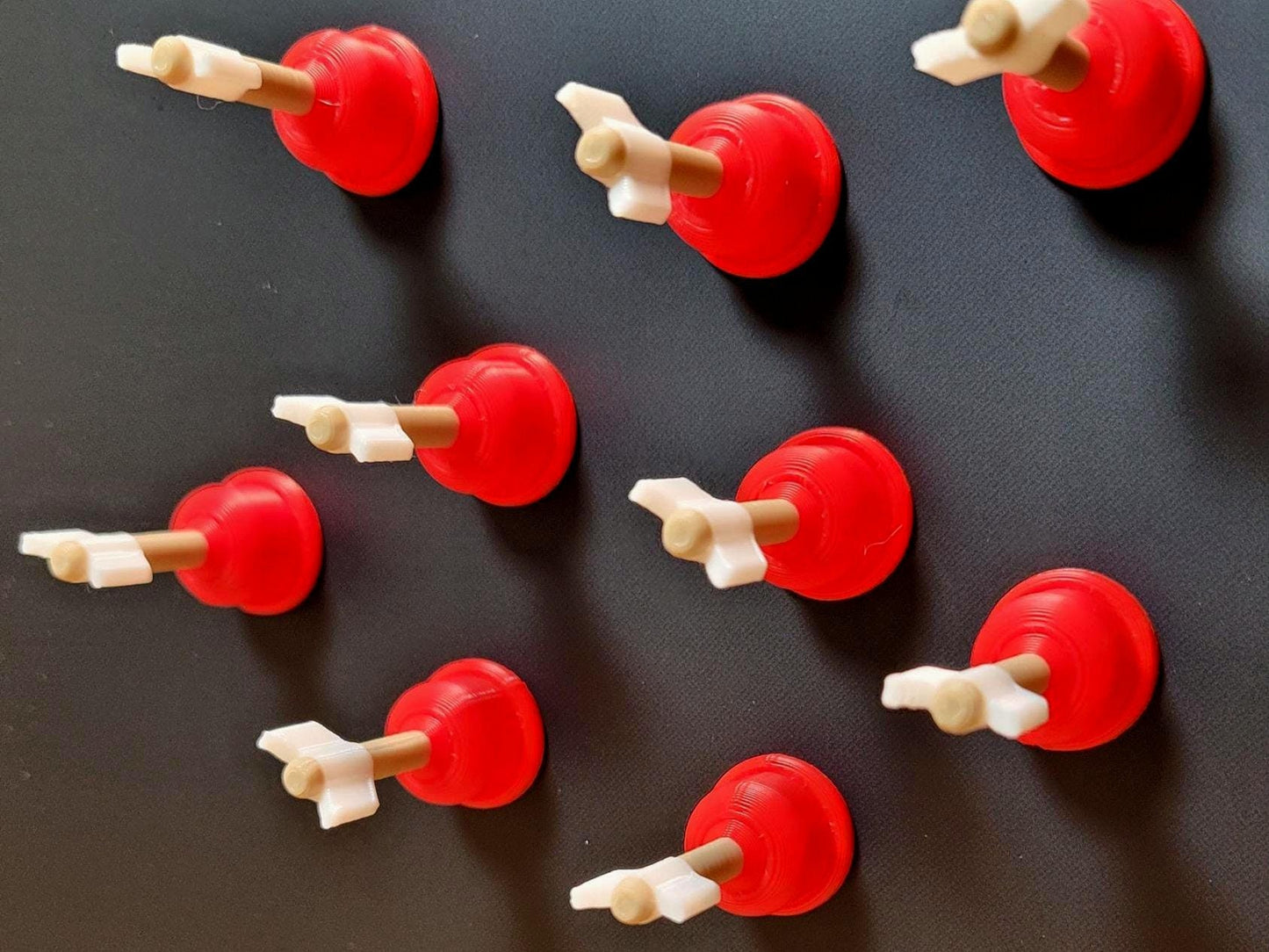 Set of mini plunger arrow fridge magnets shown from above, with red bases, gold shafts, and white arrow tips.