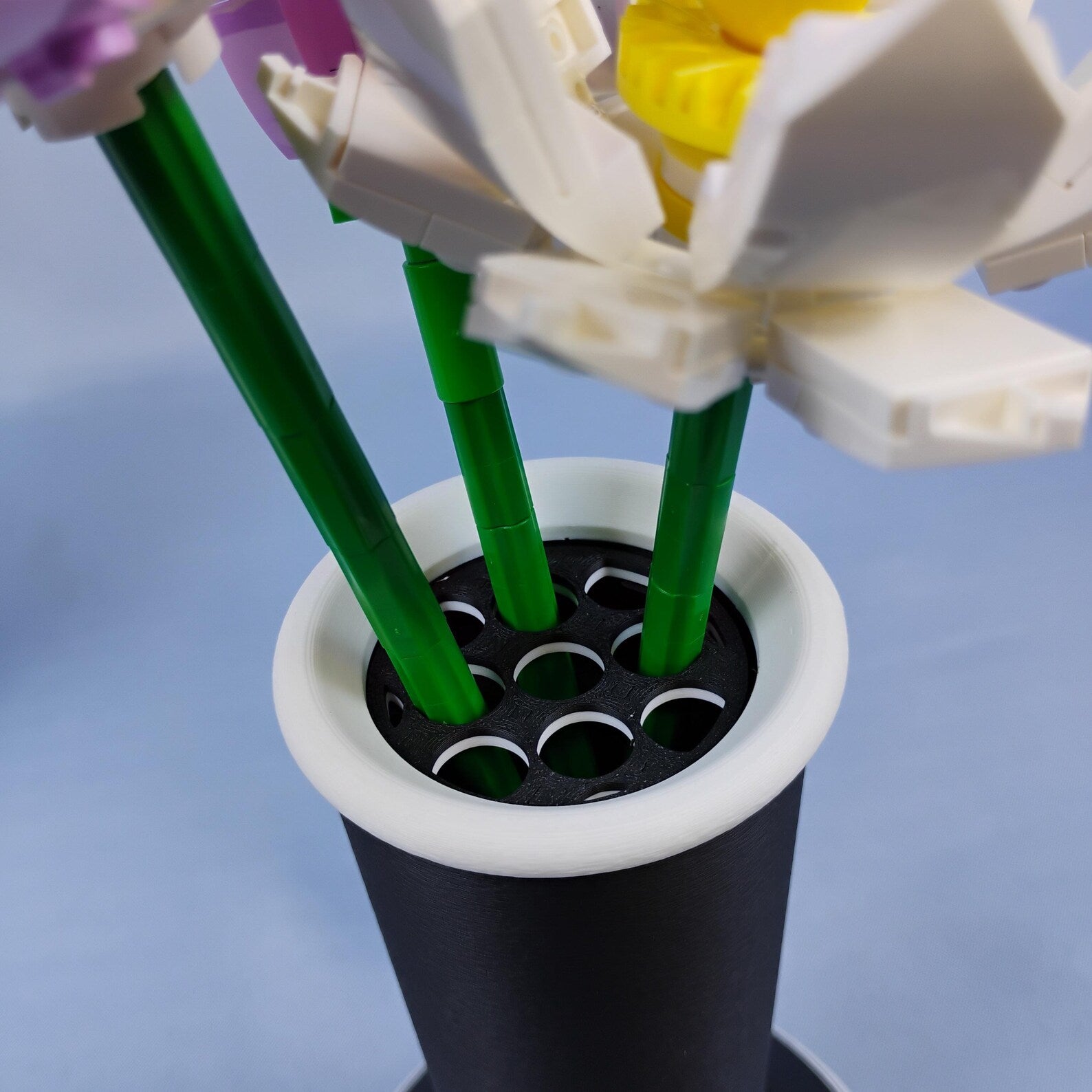 Close-up of LEGO® botanical stems placed into the removable grid insert of a minimalist vase