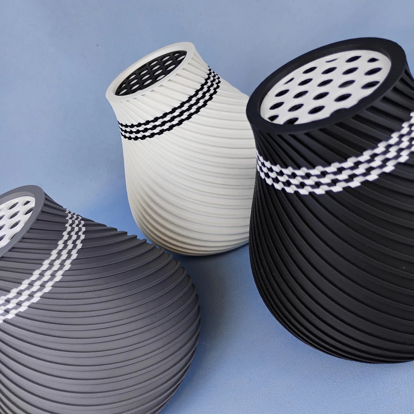 Black, white, and gray swirly vases shown together with removable grid inserts