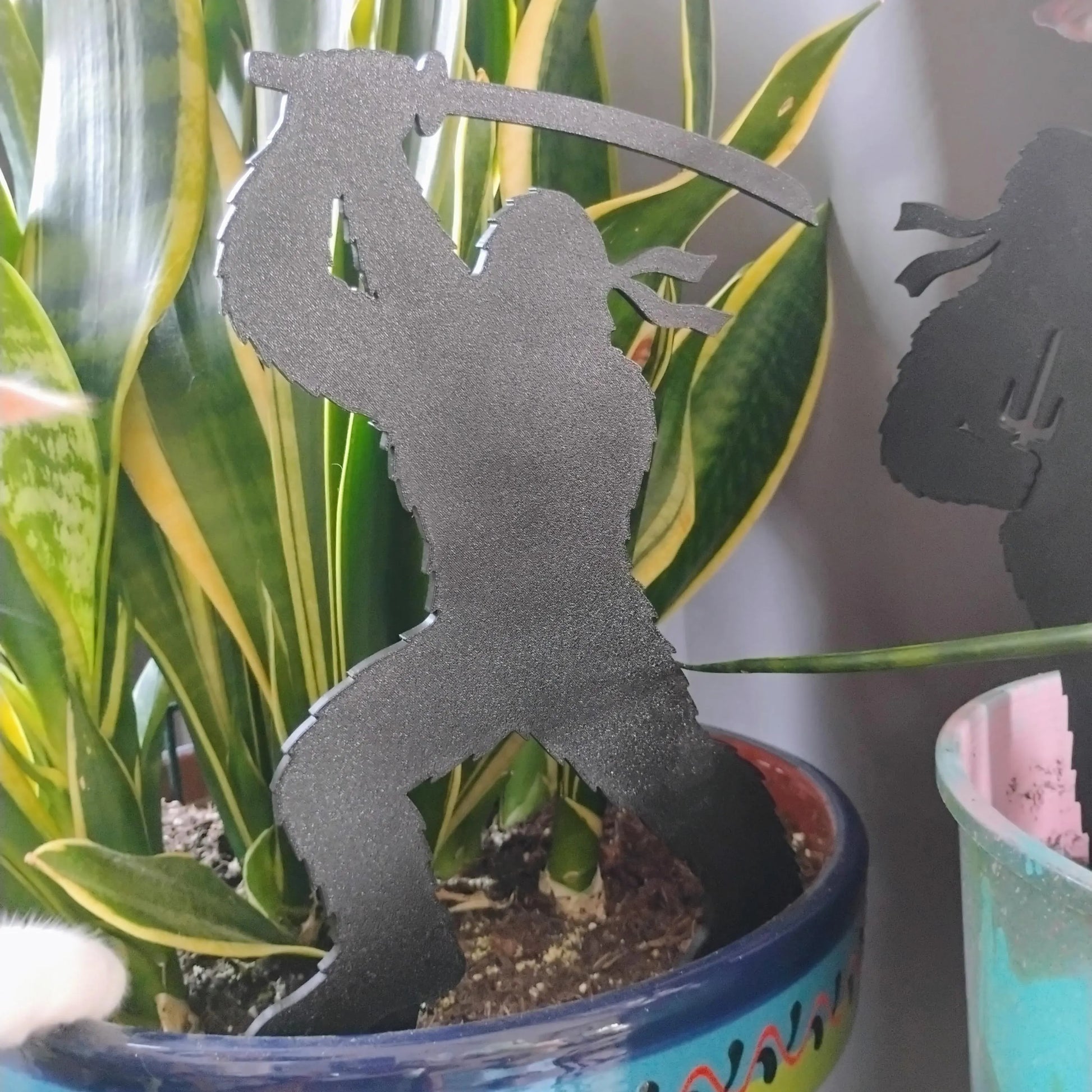 Black Ninja Bigfoot Garden Spike standing inside a decorative indoor houseplant pot.