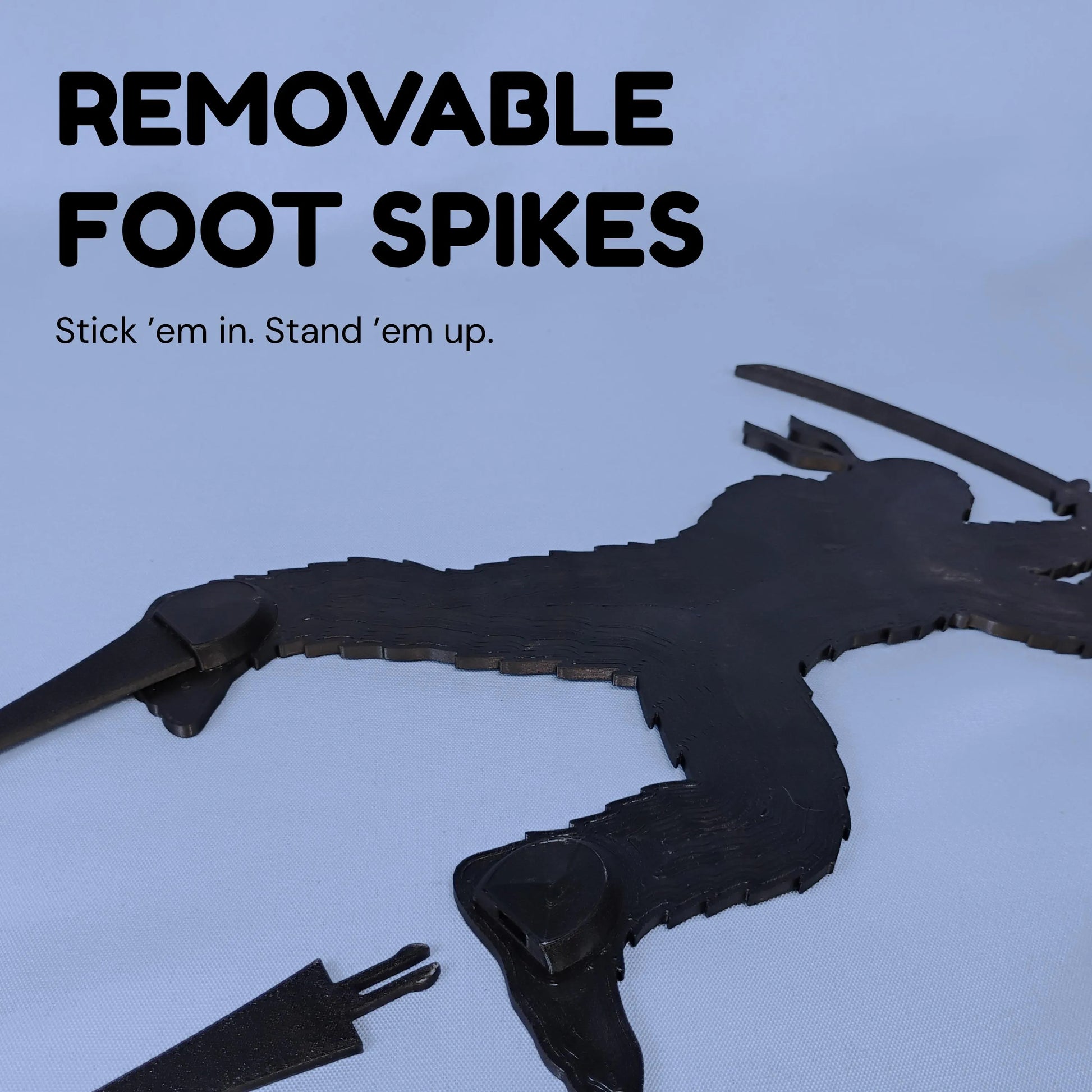 Close-up demonstration of removable ground spikes sliding into slots beneath a Ninja Bigfoot figure’s feet.
