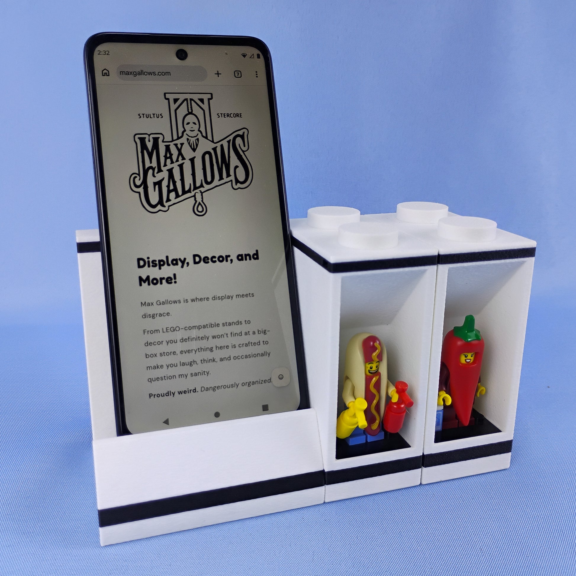 White modular phone stand connected to a two-minifigure display brick with LEGO® figures beside the smartphone.