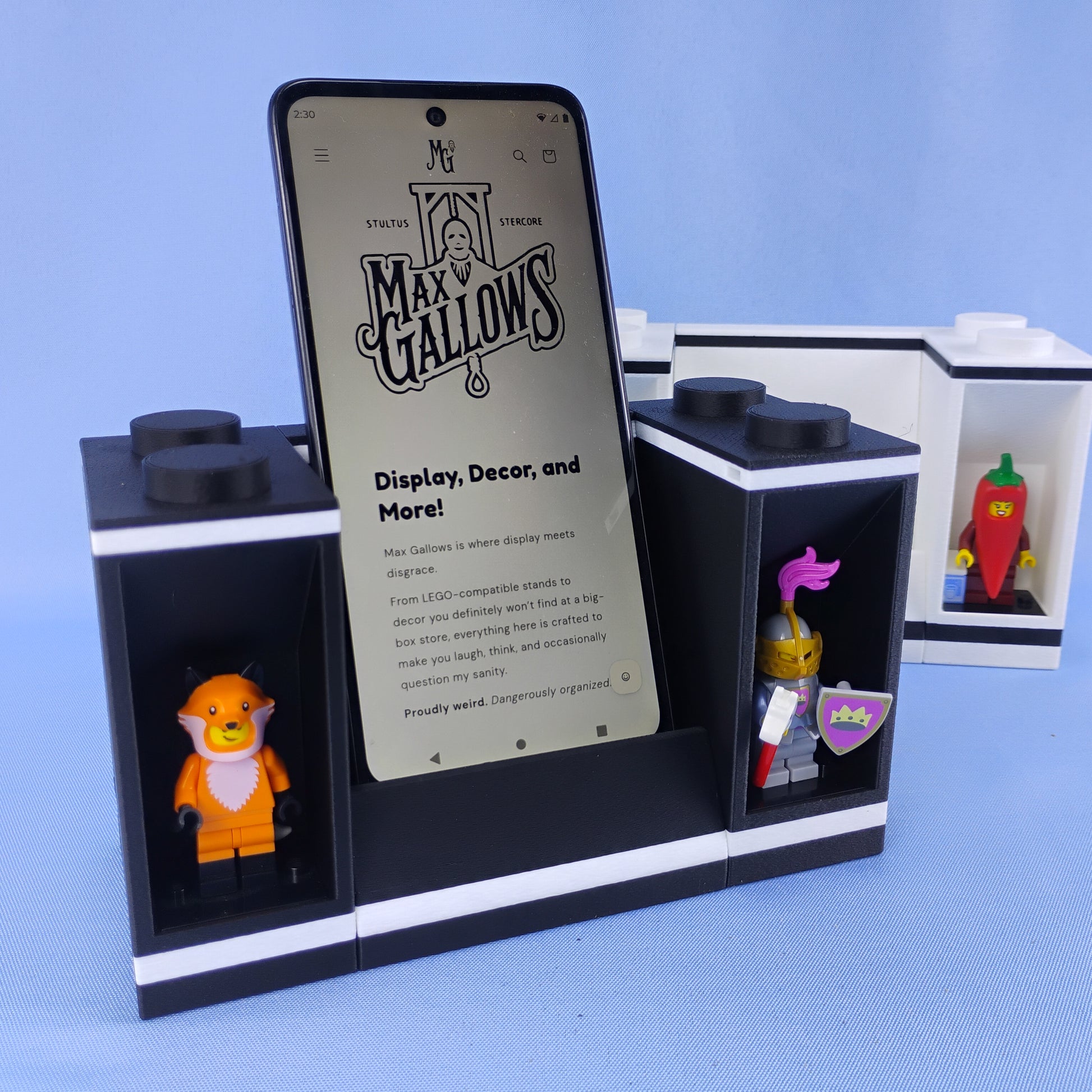 Modular phone stand with LEGO® minifigure display bricks on both sides, shown with a smartphone and colorful minifigures.