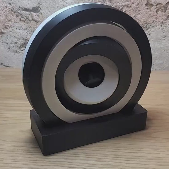 Video showing a large black and white kinetic fidget toy on its display base