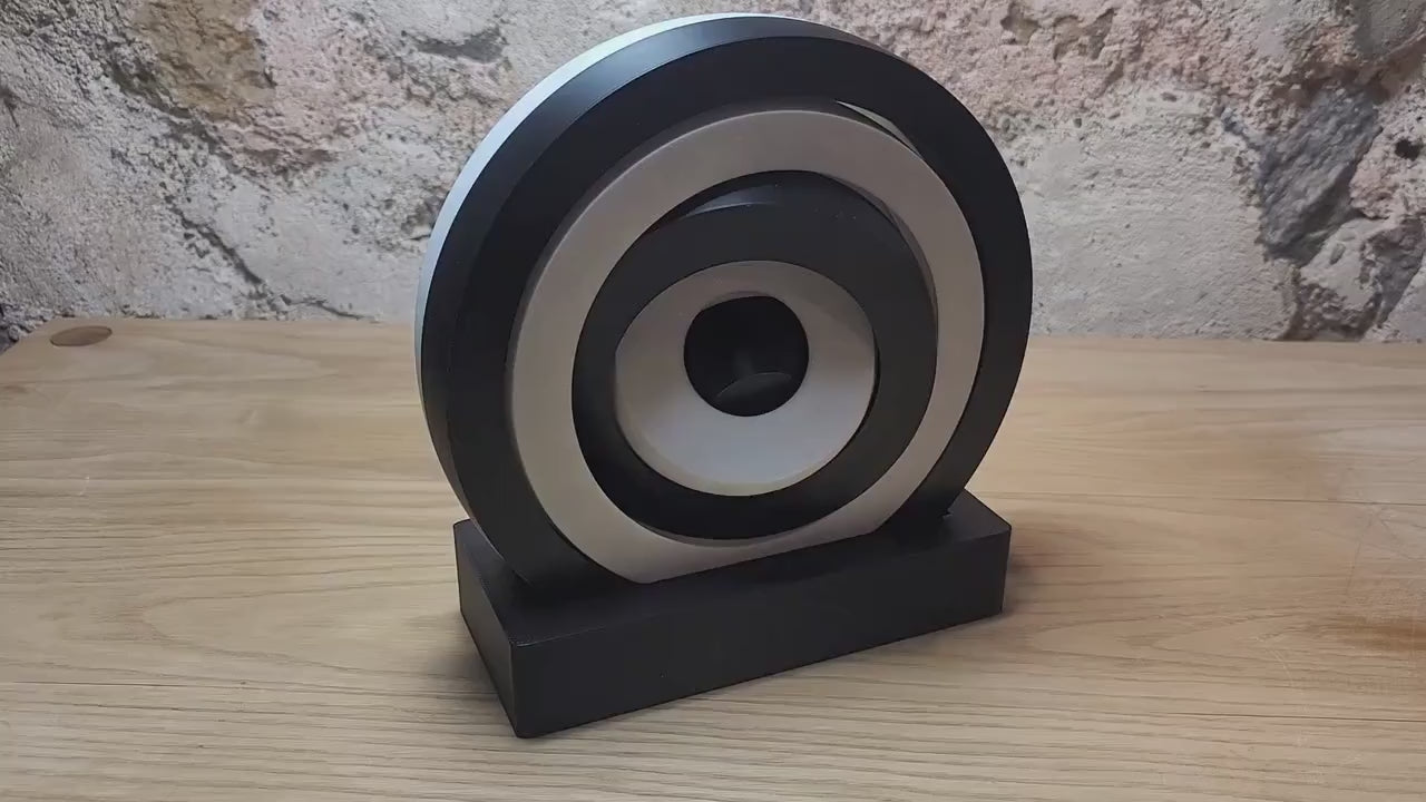 Video showing a large black and white kinetic fidget toy on its display base