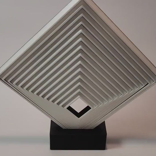 Video showing a large geometric fidget square on a black display stand