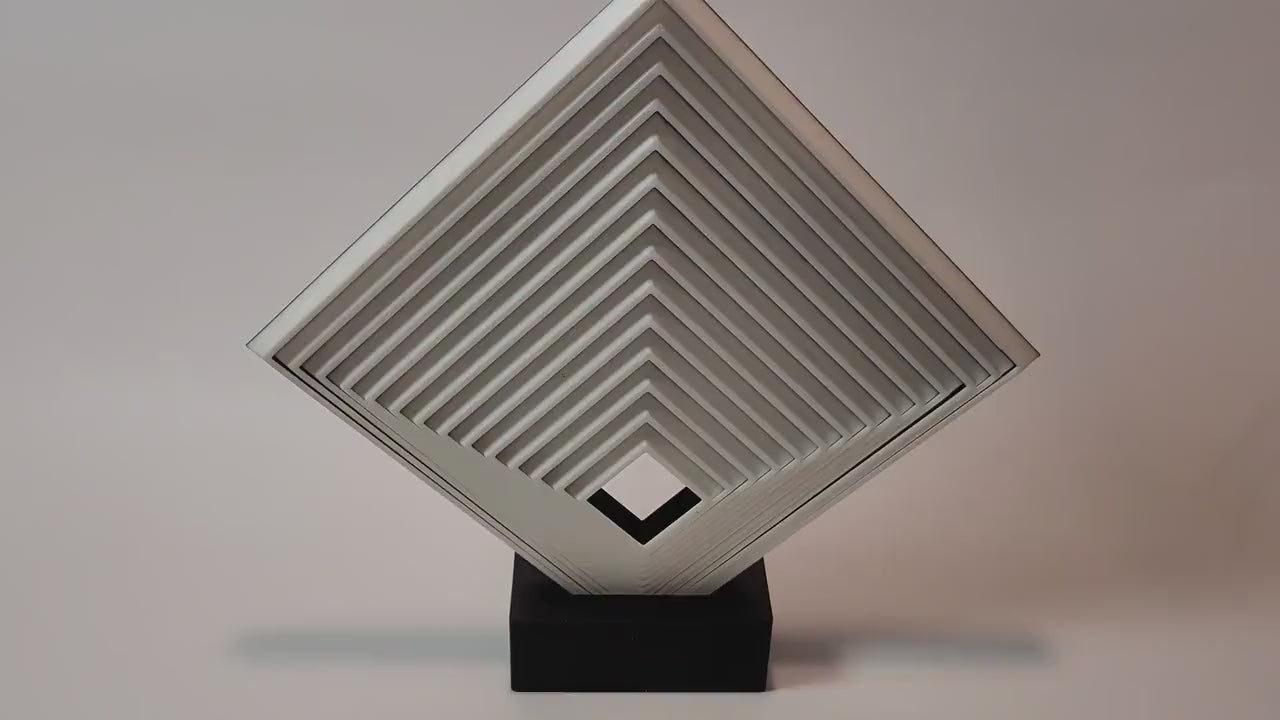 Video showing a large geometric fidget square on a black display stand