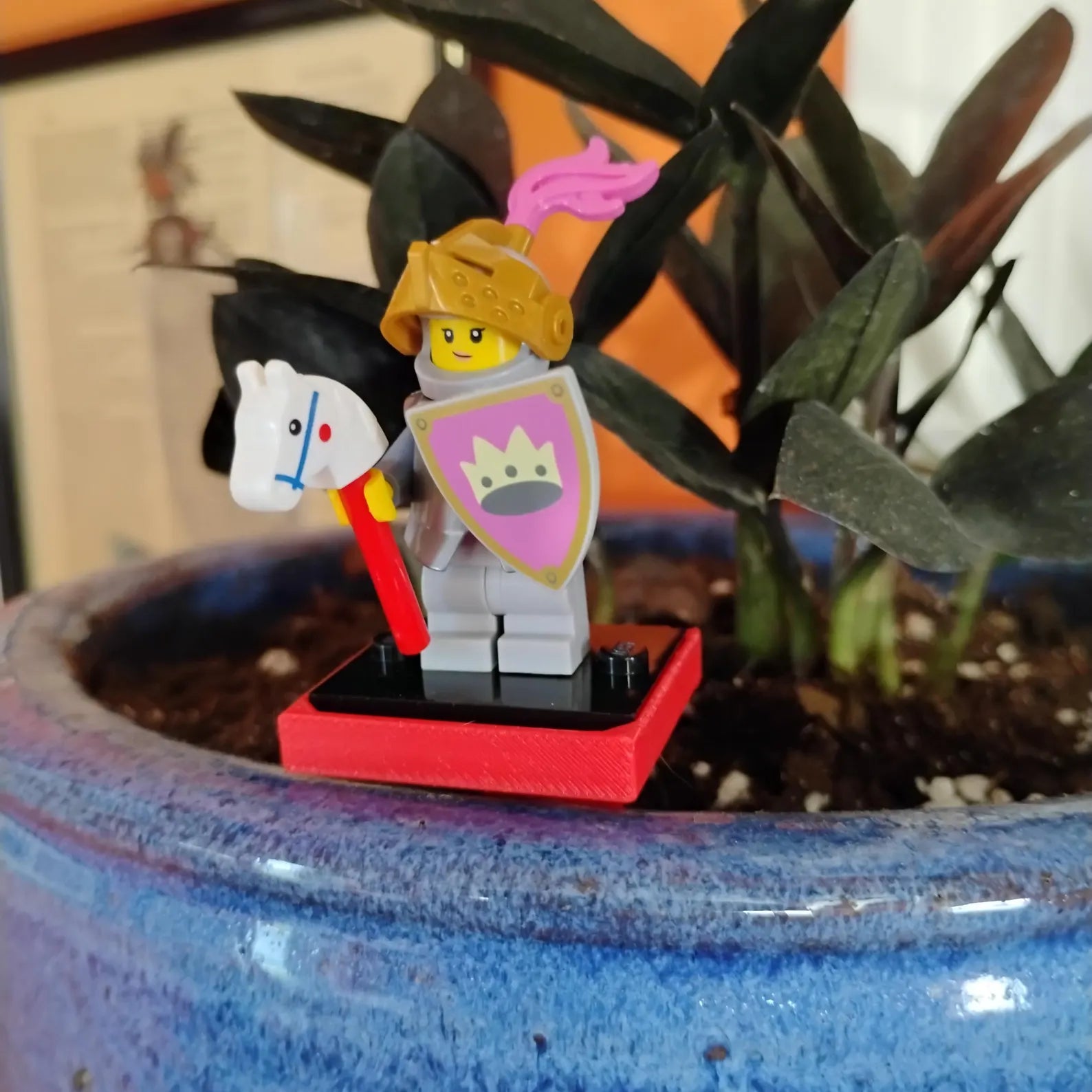 Red plant stake holding a LEGO® minifigure in a blue planter