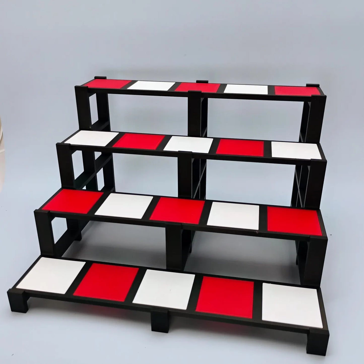Red, white, and black tiered display stand with removable tiles, shown empty for collectibles, Funko Pops, and shelf displays.