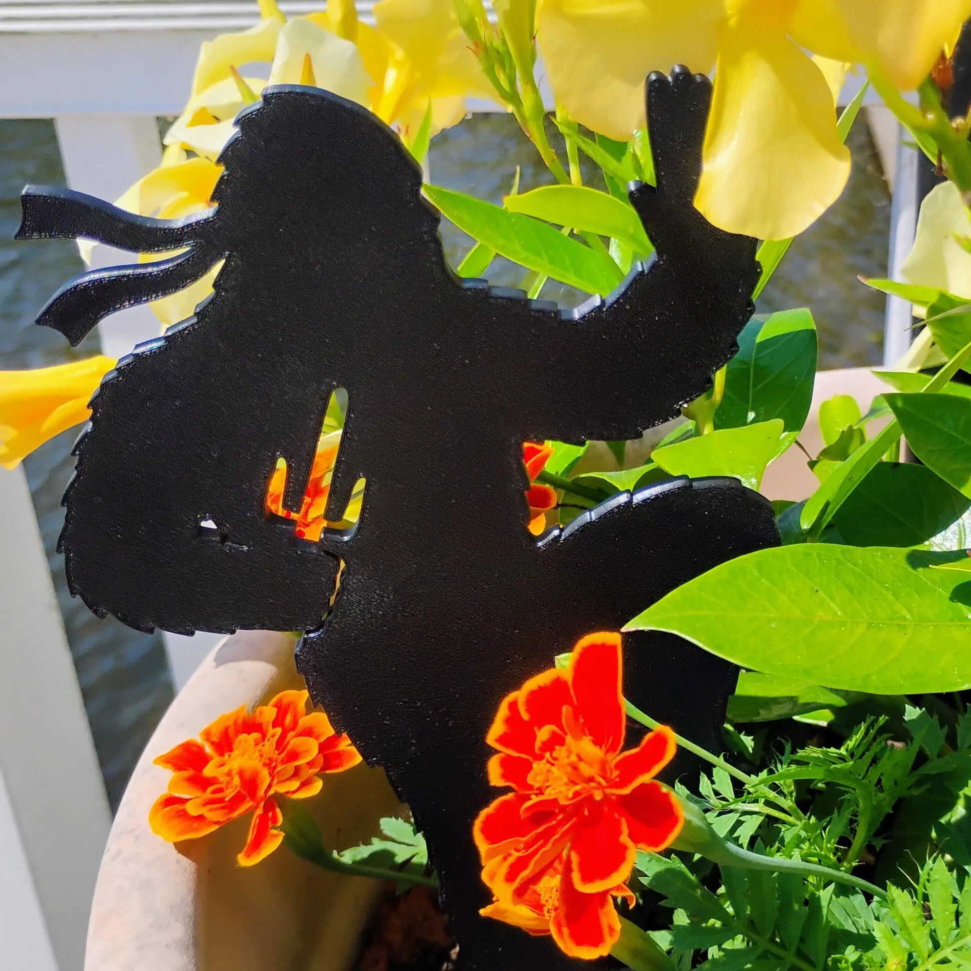 Sai-Squatch Ninja Bigfoot Garden Spike displayed outdoors among green leaves and orange flowers.