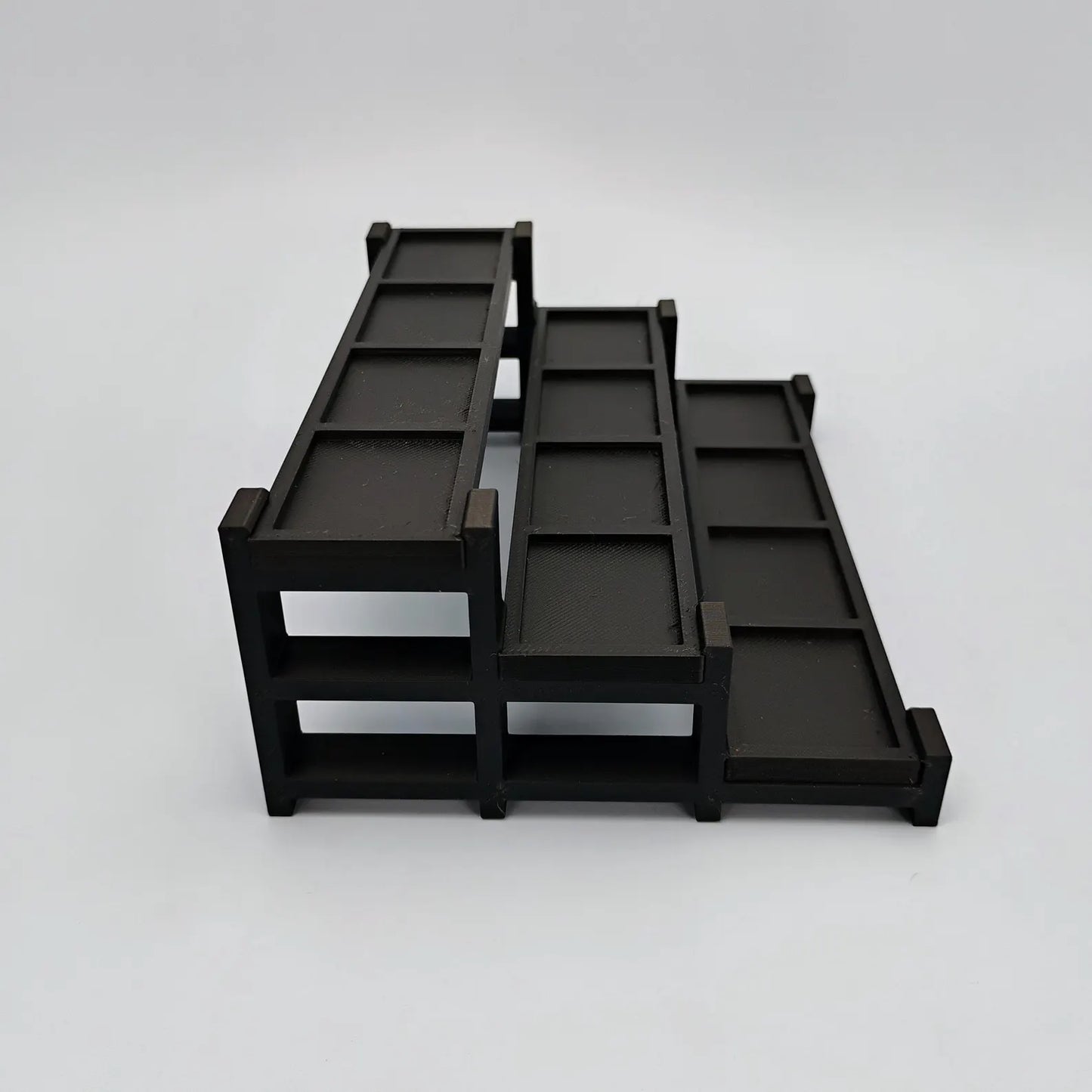 Side view of a black tiered display stand showing the depth and stepped layout for LEGO® minifigures.