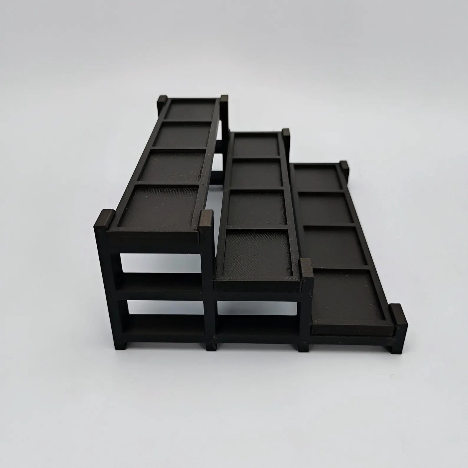 Side view of a black tiered display stand showing the depth and stepped layout for LEGO® minifigures.