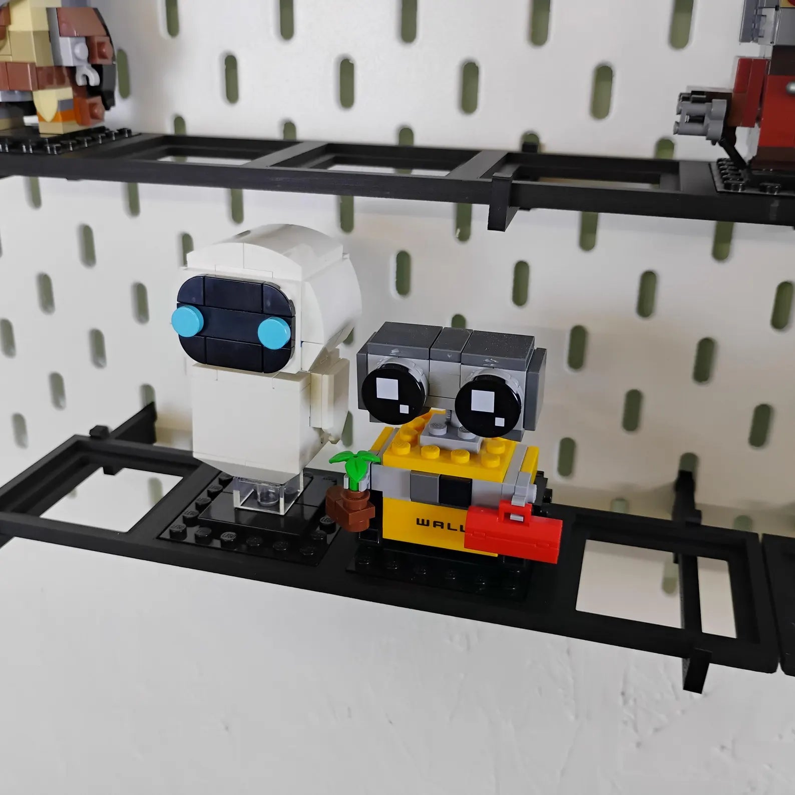 SKÅDIS-compatible BrickHeadz™ shelf mounted on a pegboard with a single LEGO® BrickHeadz™ figure displayed on a black shelf.