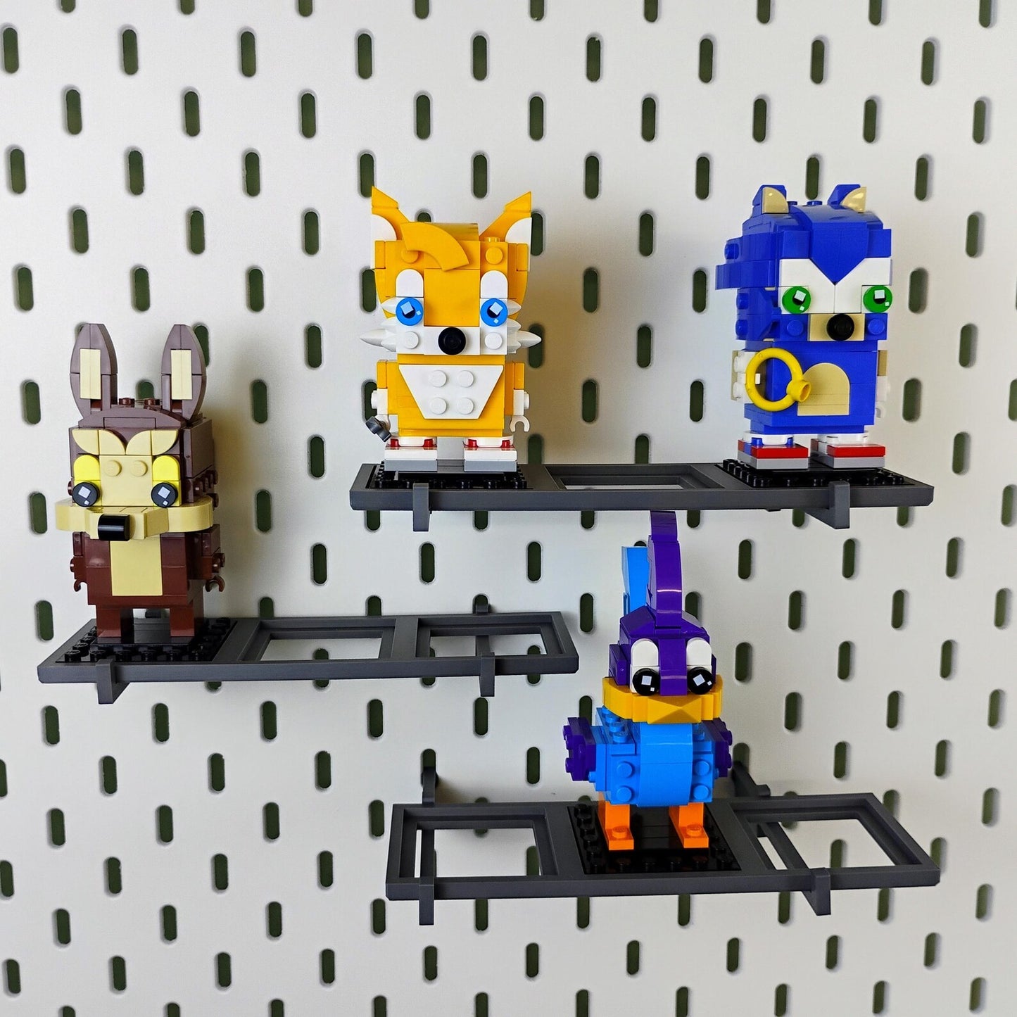 Mixed-width SKÅDIS-compatible shelves displaying LEGO® BrickHeadz™ figures on an IKEA pegboard collector wall.