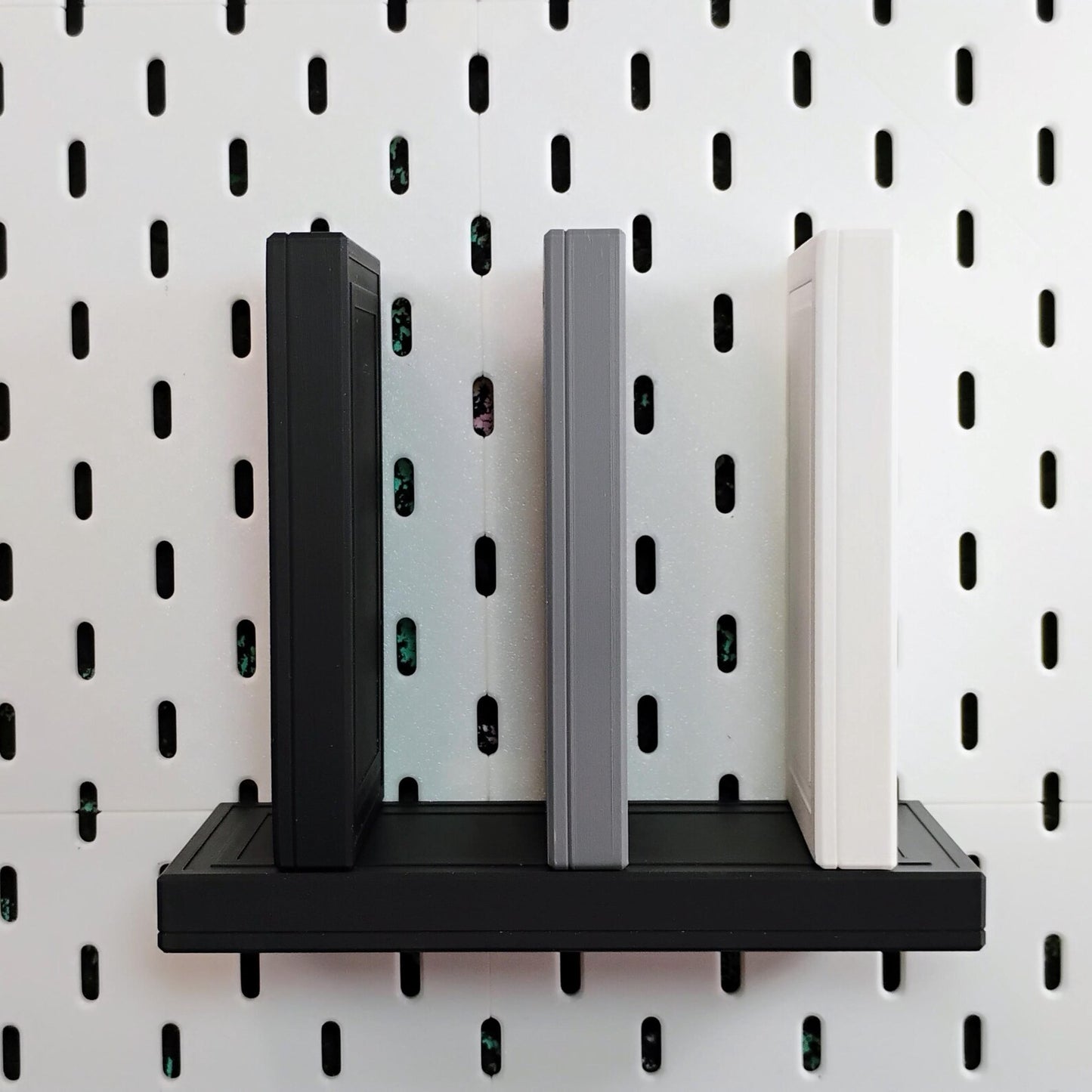 Black SKADIS floating shelf holding other shelves with gray and black shelf supports