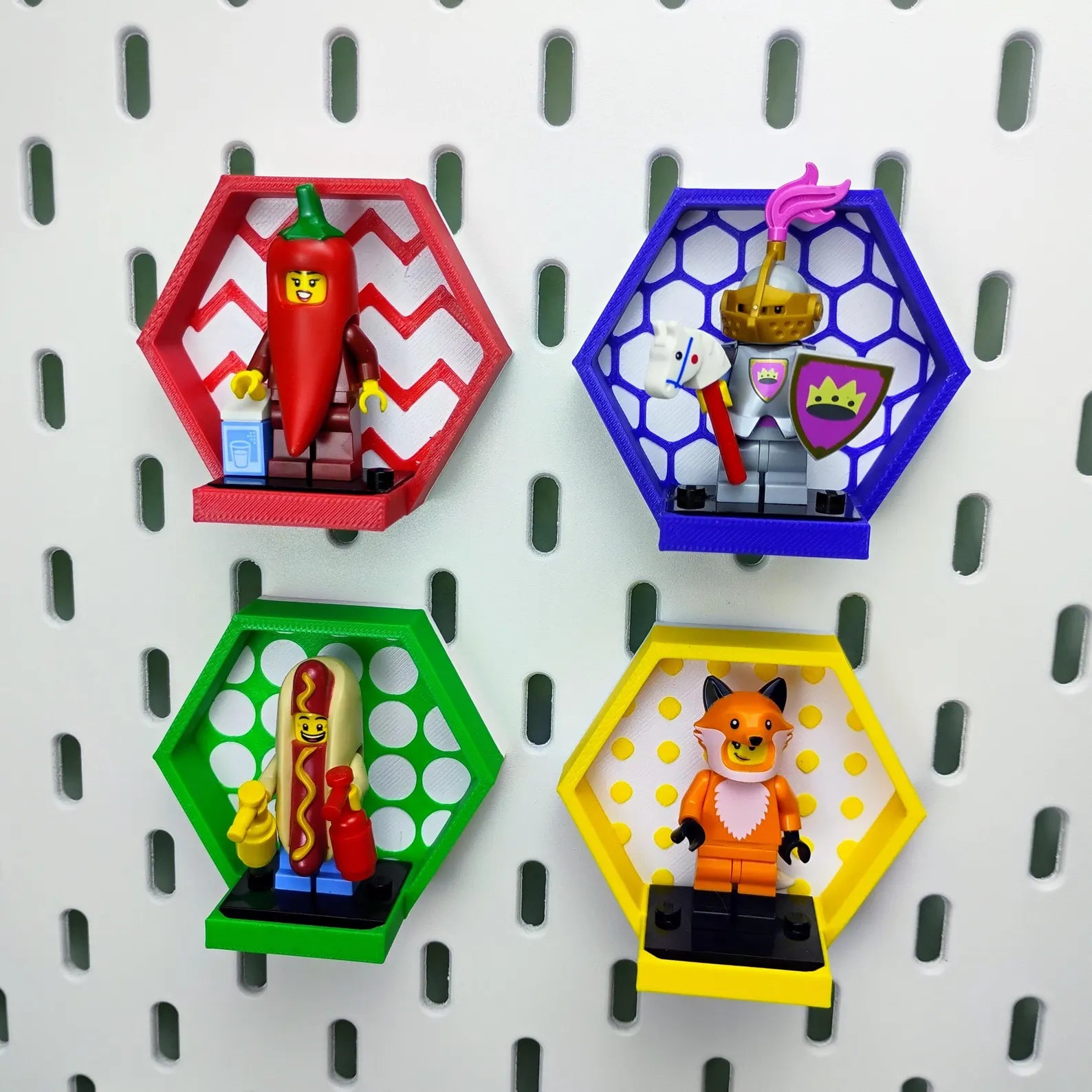 Four colorful SKÅDIS-compatible hexagon minifigure displays mounted on a pegboard with red, blue, green, and yellow frames.