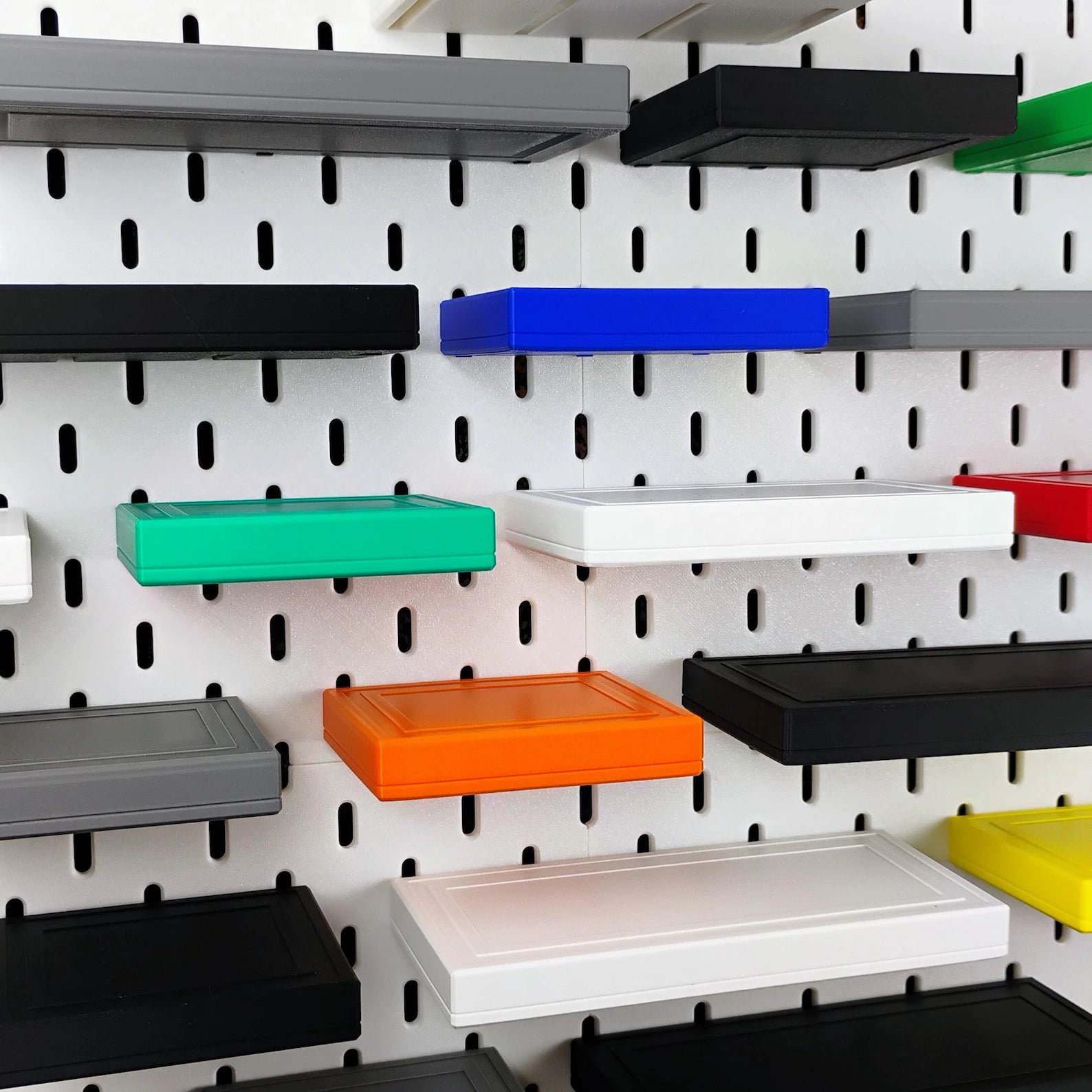 Assorted floating shelves mounted on IKEA SKADIS pegboard for wall storage