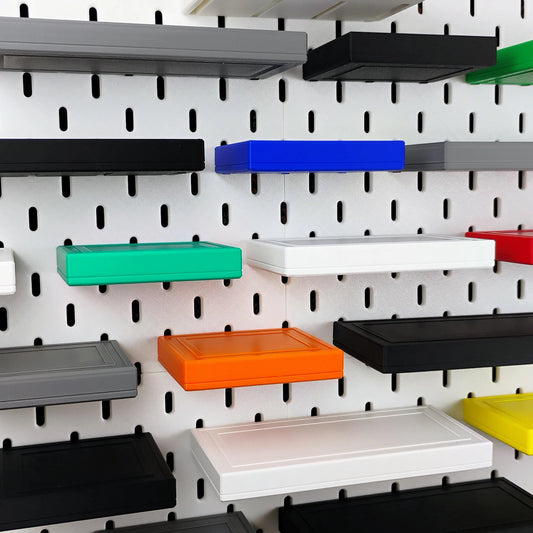 Assorted floating shelves mounted on IKEA SKADIS pegboard for wall storage
