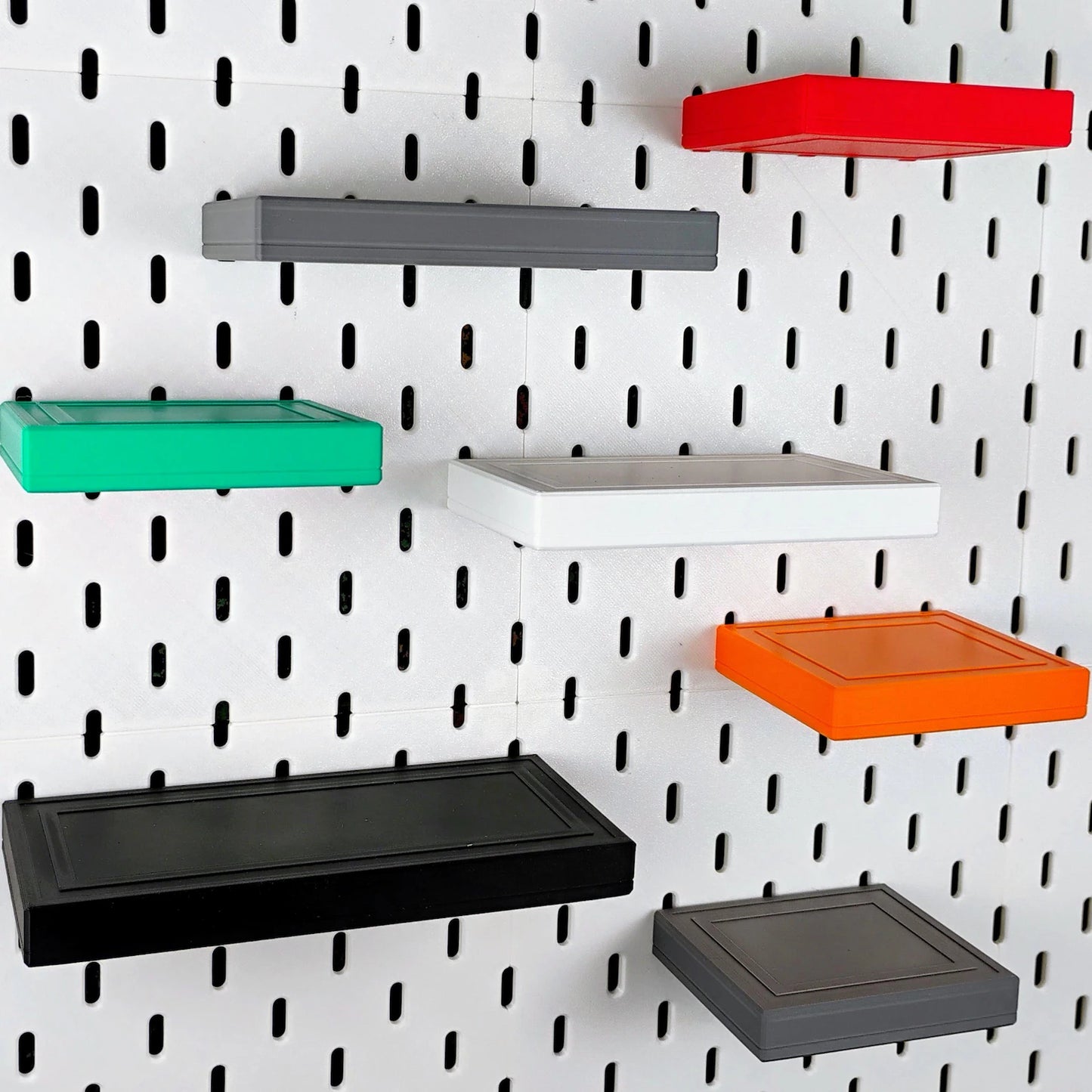 Colorful floating shelves arranged on an IKEA SKADIS pegboard wall