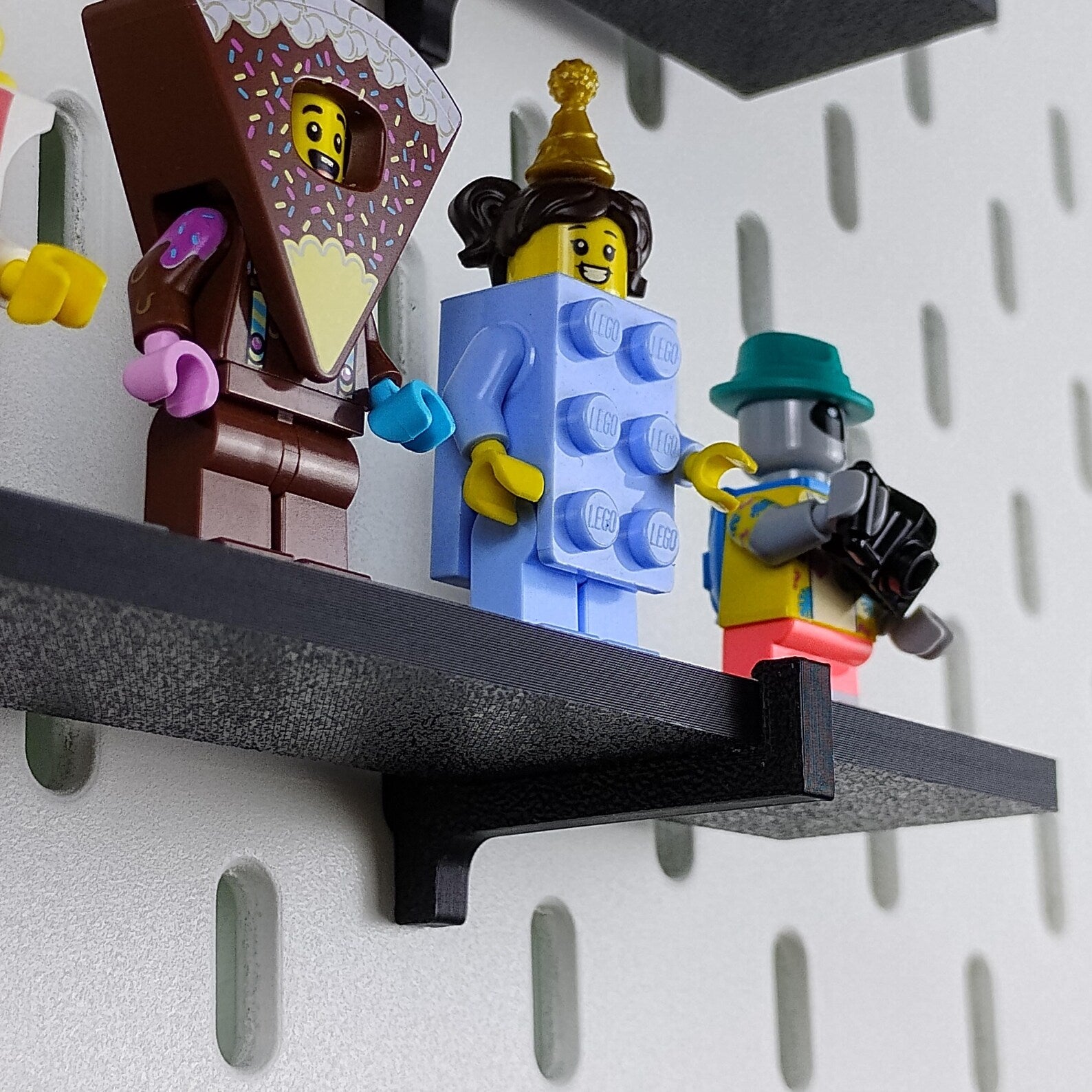 Close-up of LEGO® minifigures displayed on a SKADIS shelf mounted to pegboard