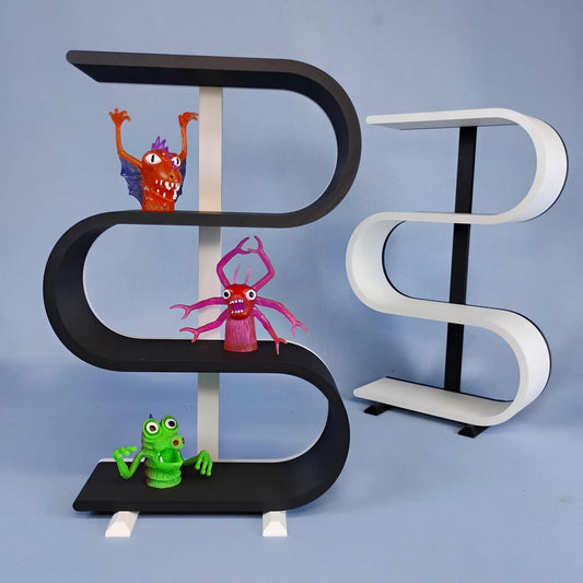 Black and white squiggly display shelves shown together with colorful monster figures. The freestanding three-tier shelves have removable feet and curved display surfaces for trinkets, mini collectibles, small figures, crystals, and desk decor.
