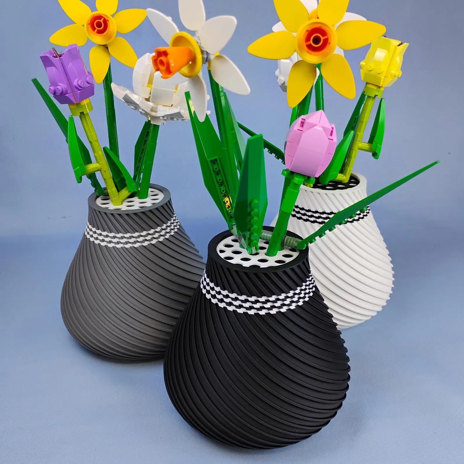 Black, white, and gray swirly vases displaying LEGO® botanical flower bouquets