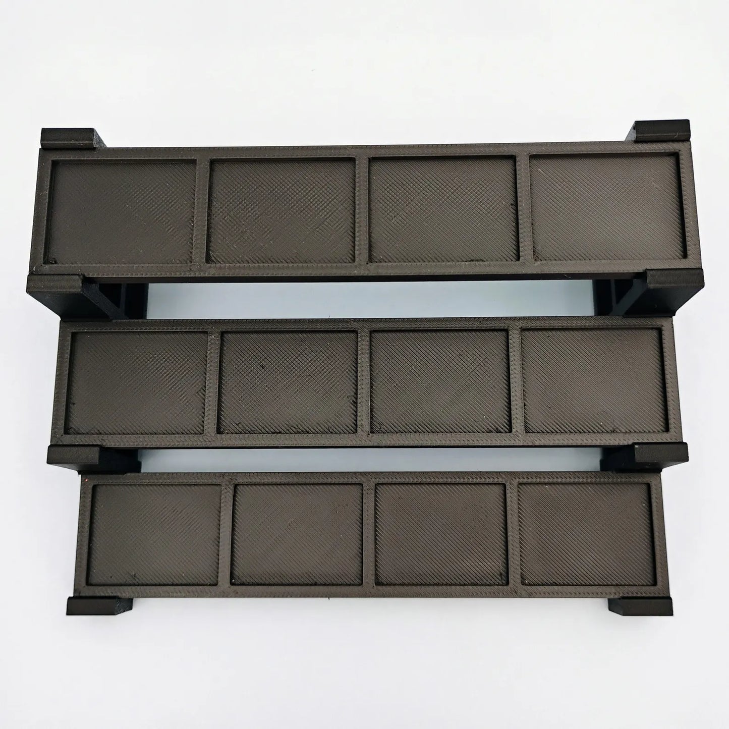 Top view of a black tiered minifigure display stand showing the stepped shelf layout and plate spaces.