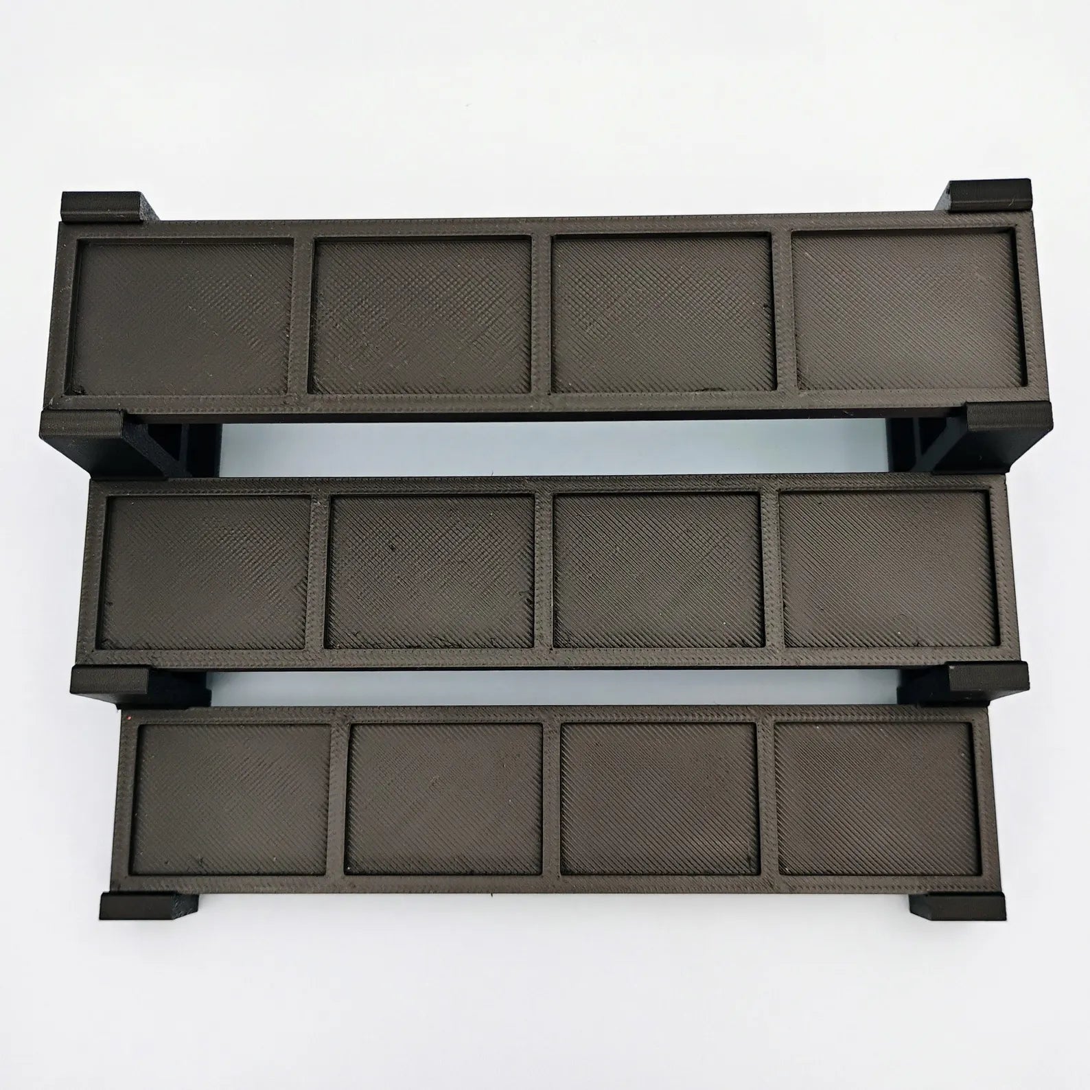Top view of a black tiered minifigure display stand showing the stepped shelf layout and plate spaces.