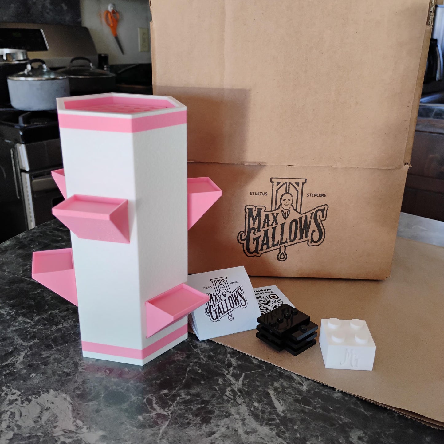 White and pink geometric vase with 'Max Gallows' branding on a kitchen counter.