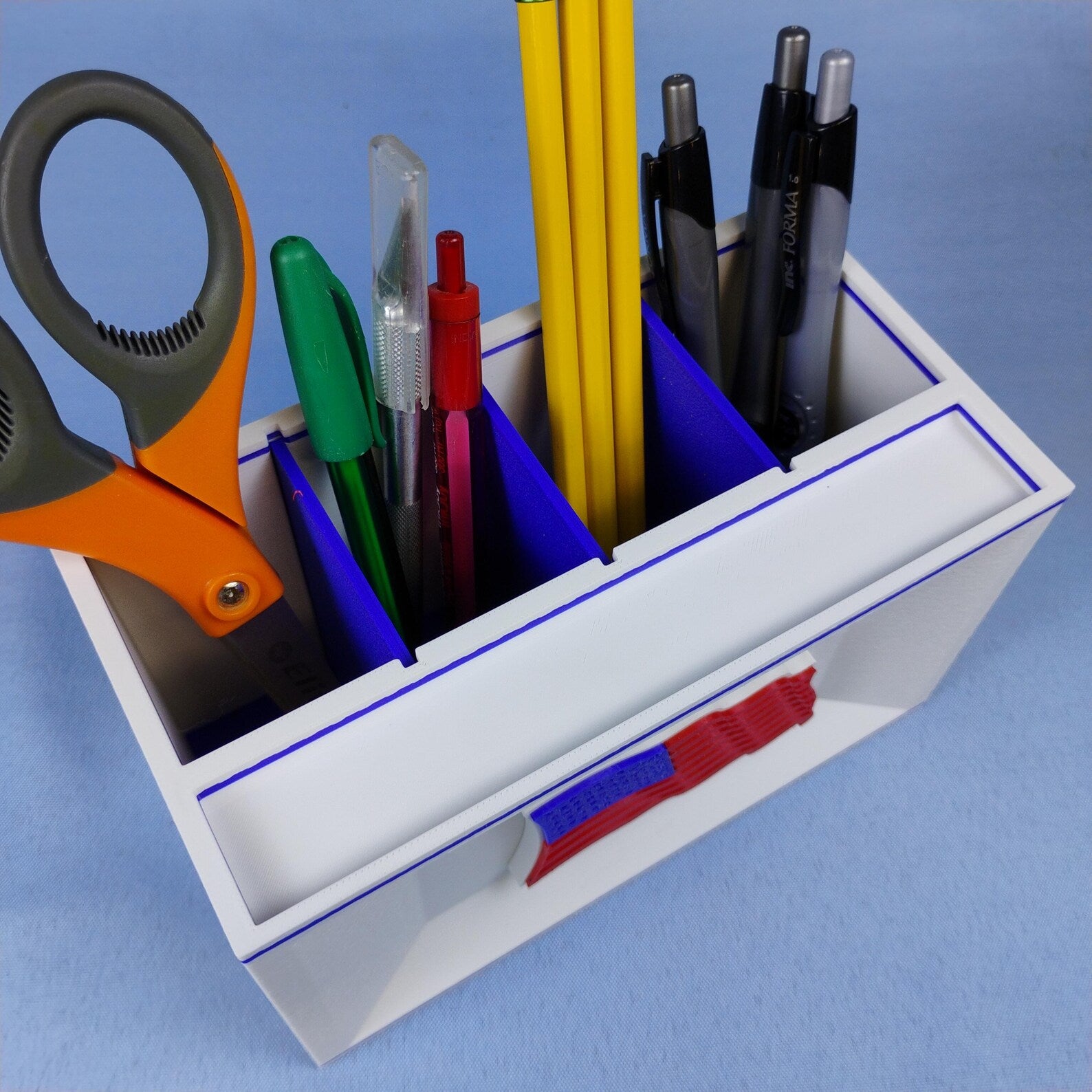 White American flag desk organizer shown from above with pens, pencils, and scissors