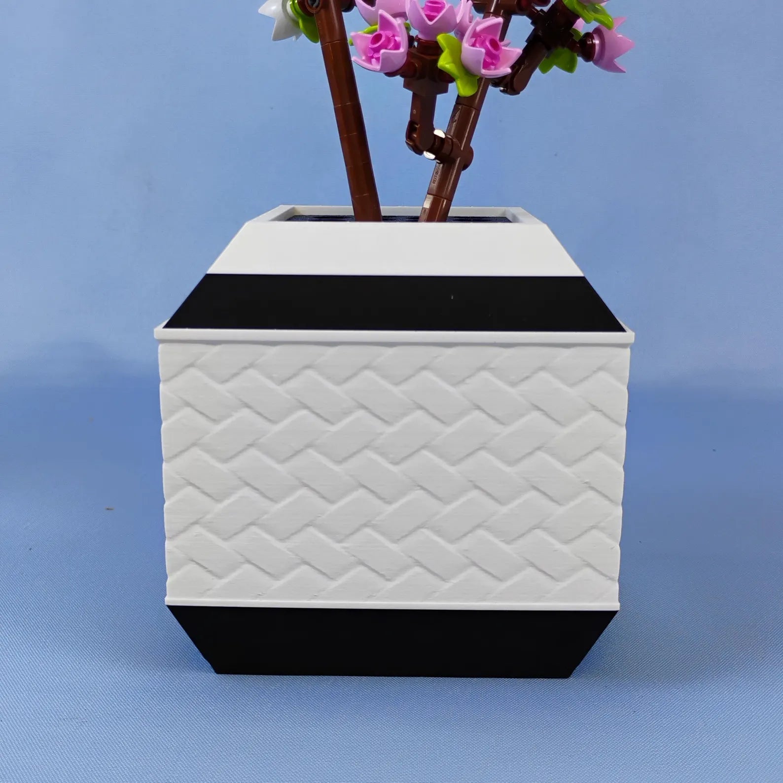White geometric vase holding LEGO® cherry blossoms on a blue background