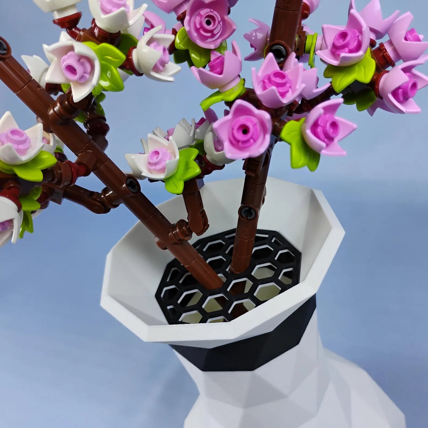White geometric vase with LEGO® cherry blossom stems placed in the removable grid insert