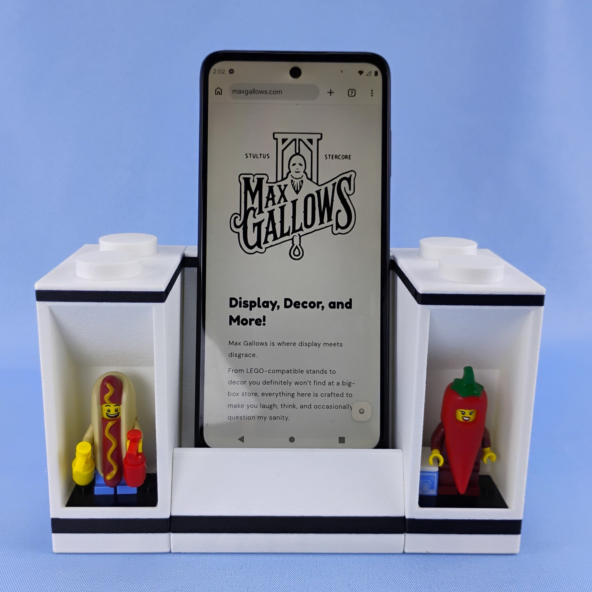 White phone stand with two LEGO® minifigure display modules positioned beside a smartphone.
