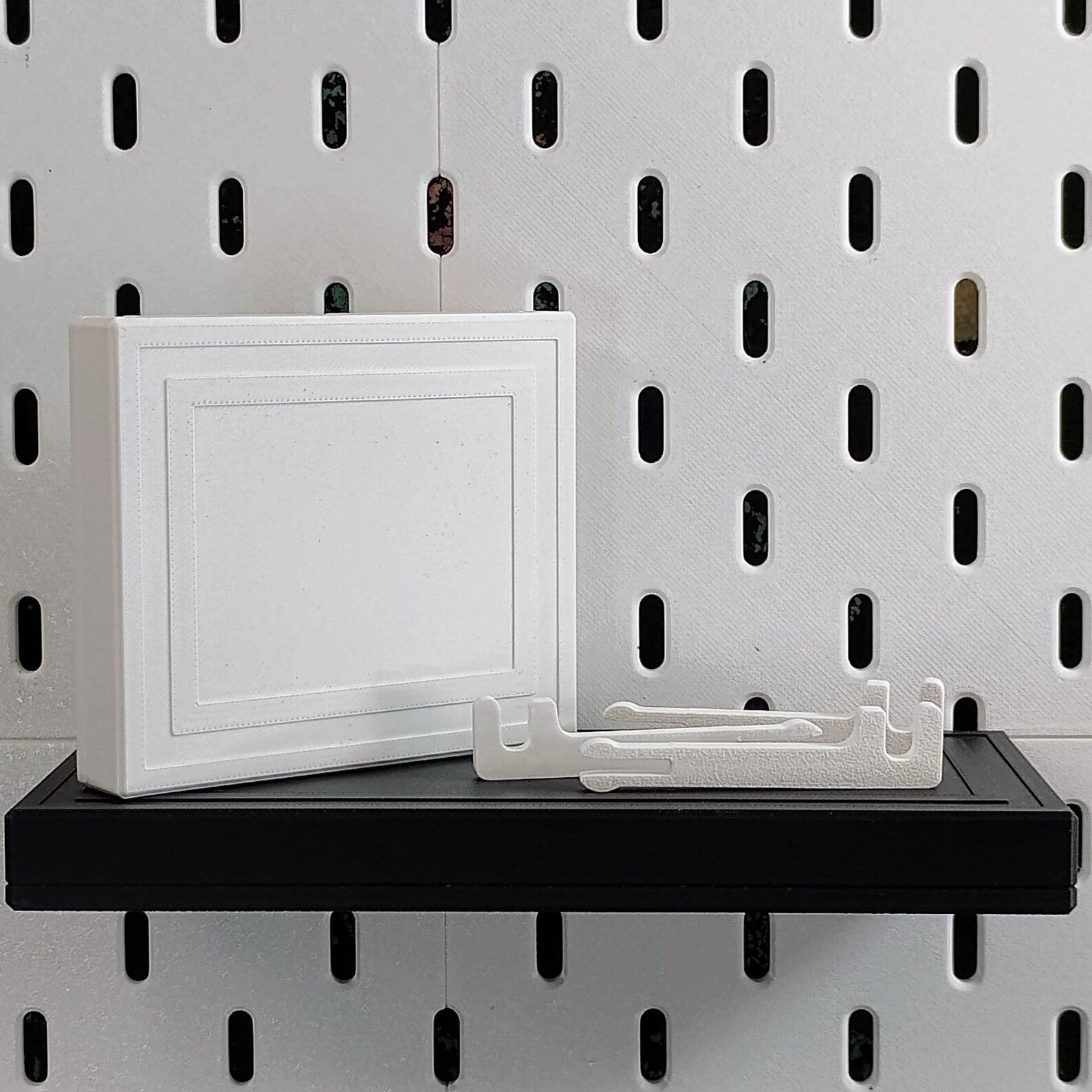 White SKADIS floating shelf shown with separate hidden click-in support pieces