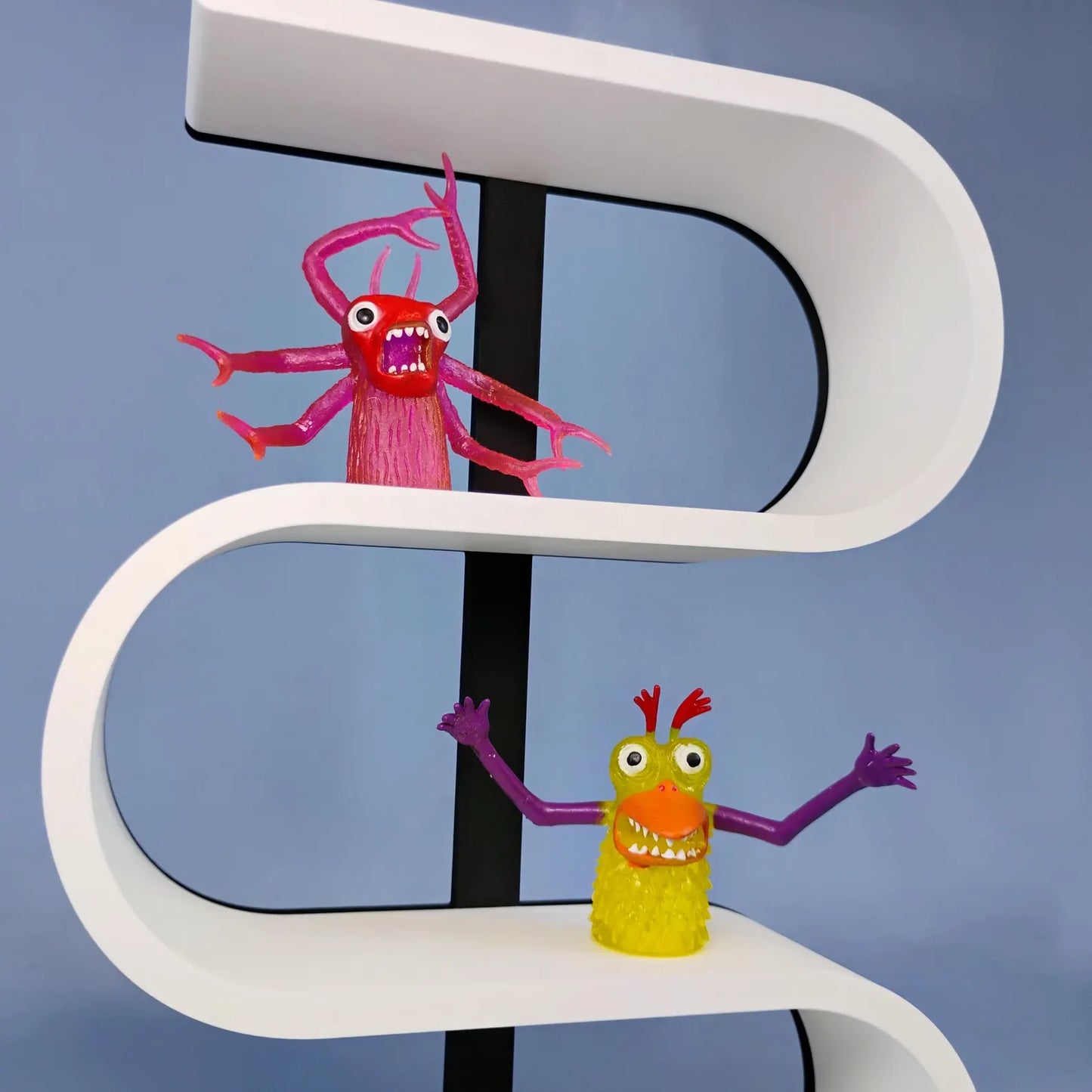 Close-up of a white squiggly display shelf with a black center support, showing colorful miniature monster figures arranged on the curved display levels.