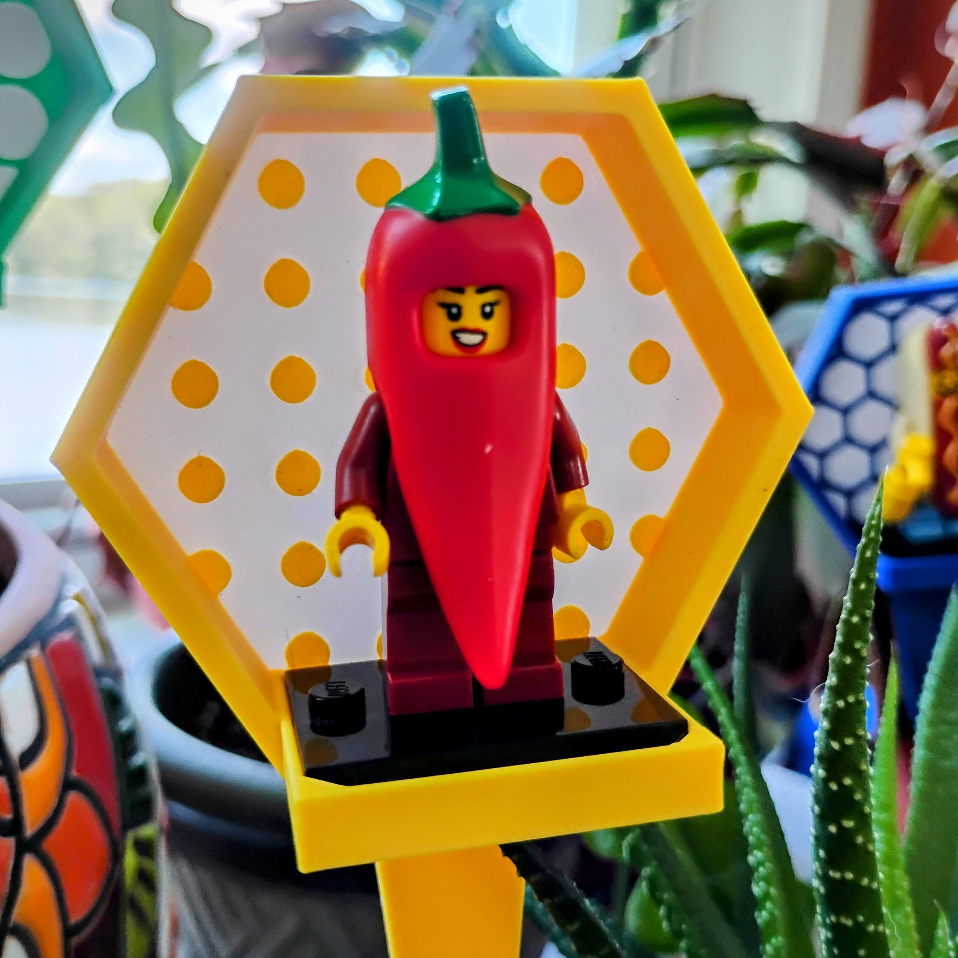 Yellow LEGO® minifigure plant stake with a circle background displaying a pepper-costume minifigure in a flowerpot.